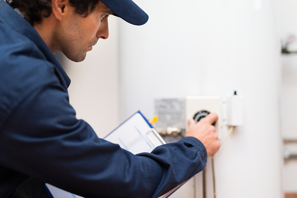 Technician in uniform adjusting the control valve on a residential water heater