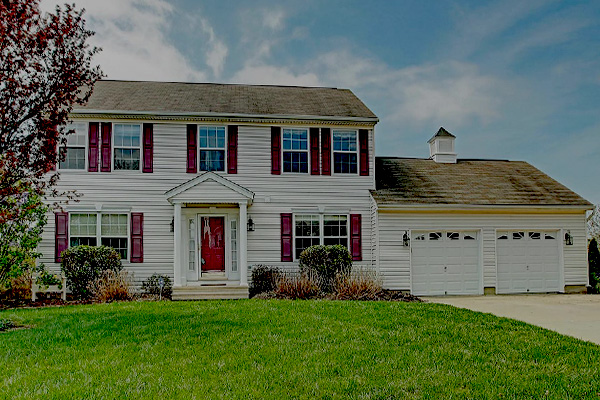 White two story colonial home with red shutters and a two car garage in Westminster, Maryland
